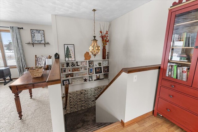 stairs with wood-type flooring and an inviting chandelier