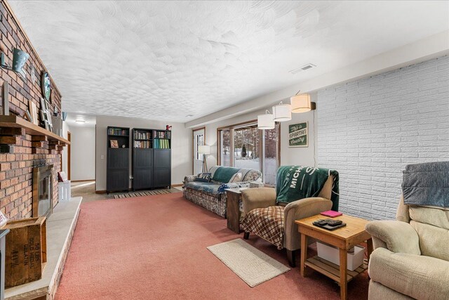 living room with brick wall, a brick fireplace, carpet, and a textured ceiling