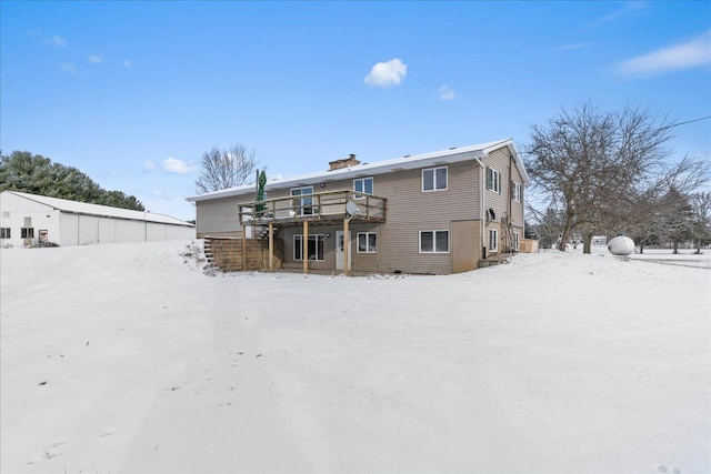 snow covered back of property with a wooden deck