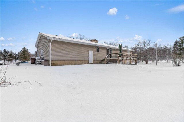 snow covered rear of property featuring a deck