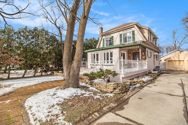 victorian home with an outbuilding, covered porch, a detached garage, concrete driveway, and a chimney