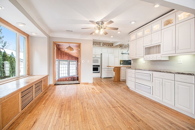 kitchen with white appliances, white cabinetry, light wood-type flooring, plenty of natural light, and glass insert cabinets