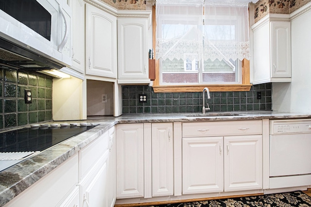 kitchen featuring white appliances, a sink, white cabinetry, and decorative backsplash