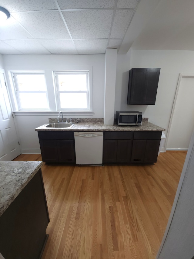 kitchen with a paneled ceiling, white dishwasher, sink, and light wood-type flooring