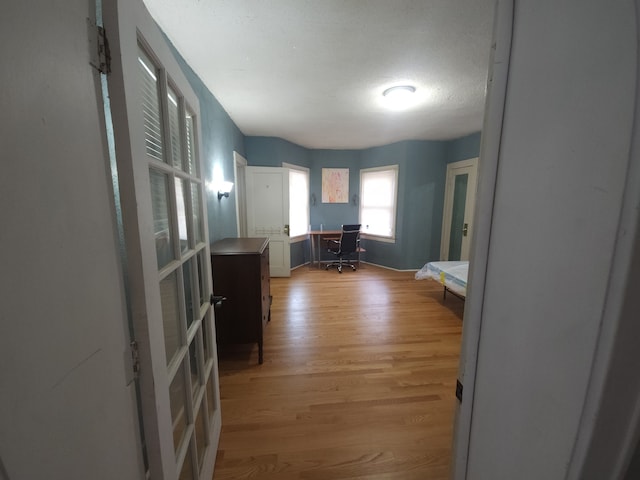 corridor with a textured ceiling and light wood-type flooring