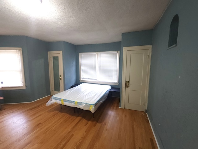 unfurnished bedroom with wood-type flooring and a textured ceiling