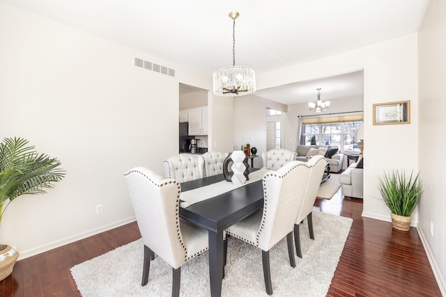 dining space with dark hardwood / wood-style flooring and a notable chandelier