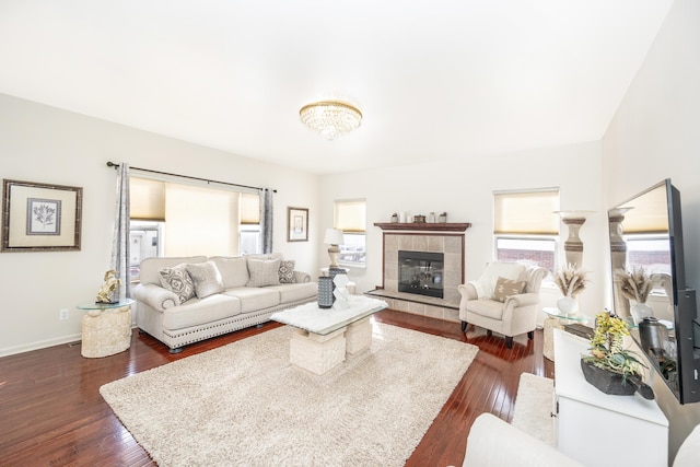 living room featuring a tiled fireplace, plenty of natural light, and dark wood-type flooring