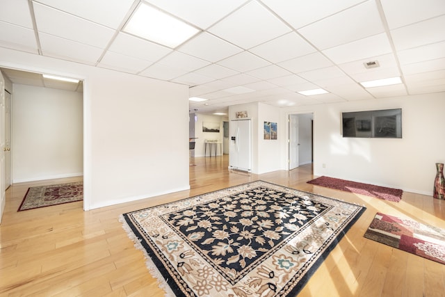 interior space featuring a paneled ceiling and light hardwood / wood-style floors