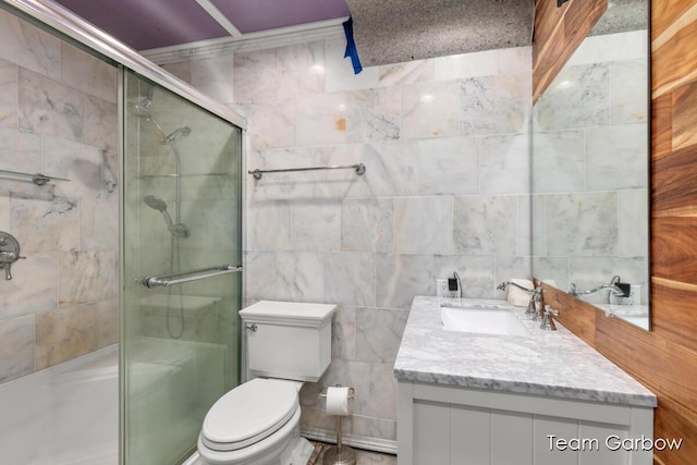 bathroom featuring walk in shower, vanity, toilet, and tile walls