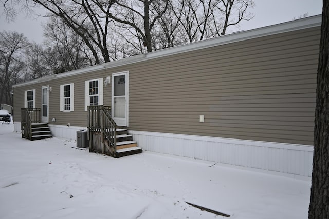 snow covered property with central AC unit