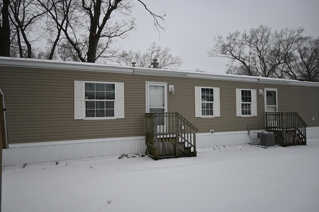 snow covered property featuring central AC