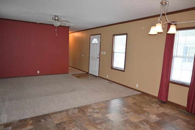 carpeted spare room featuring crown molding and ceiling fan with notable chandelier