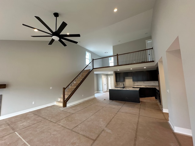 unfurnished living room with sink, ceiling fan, and a high ceiling