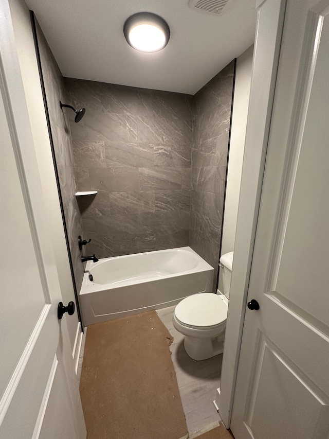 bathroom featuring toilet and tiled shower / bath