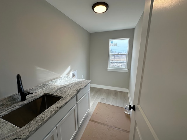 interior space with cabinets, washer hookup, sink, and light hardwood / wood-style flooring