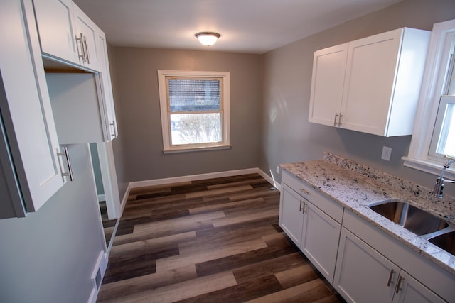 kitchen featuring light stone counters, sink, and white cabinets