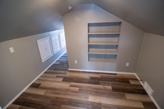 additional living space with lofted ceiling, dark hardwood / wood-style floors, and built in features