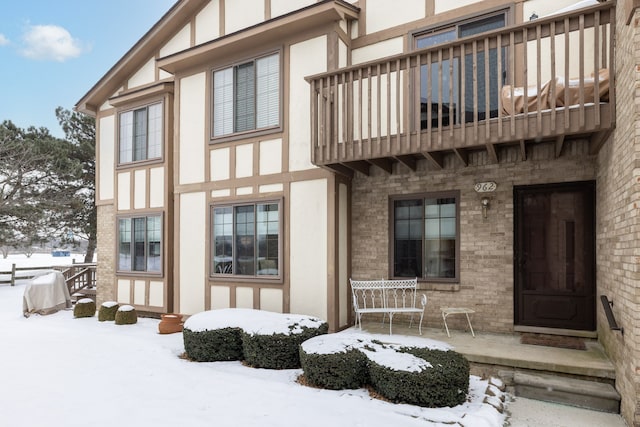 snow covered rear of property featuring a balcony