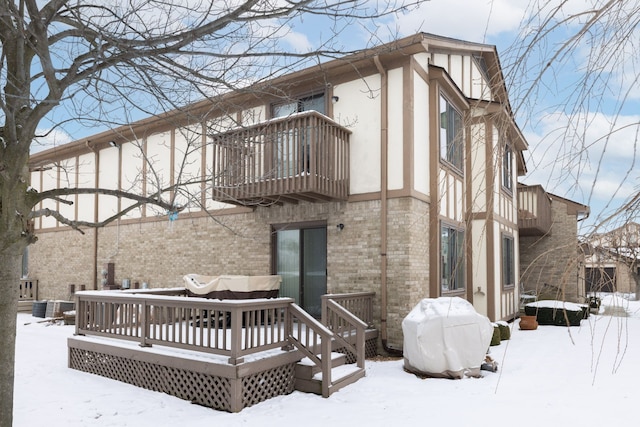 snow covered back of property featuring a wooden deck and a balcony