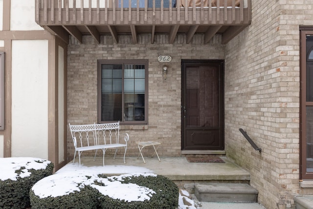 snow covered property entrance featuring a patio and a balcony