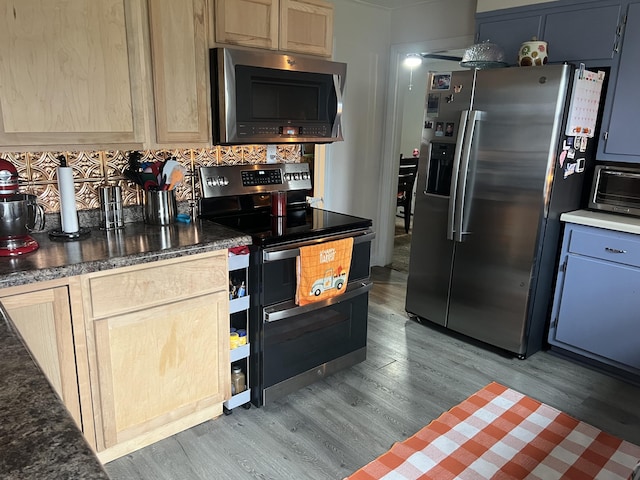 kitchen with tasteful backsplash, stainless steel appliances, light brown cabinetry, and hardwood / wood-style floors