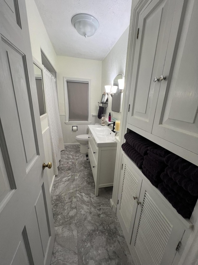 bathroom with vanity, toilet, and a textured ceiling