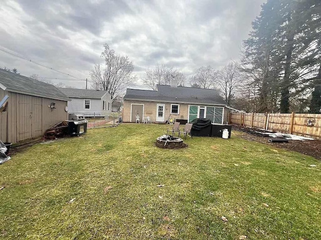 rear view of house featuring a lawn, a shed, and an outdoor fire pit