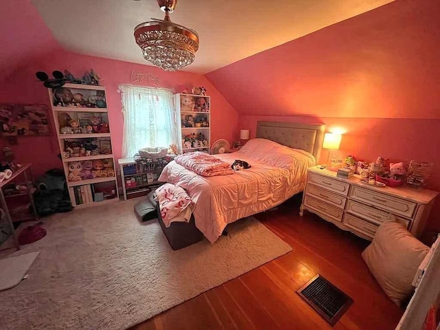 bedroom featuring vaulted ceiling, hardwood / wood-style floors, and a notable chandelier