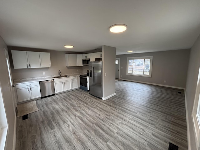 kitchen featuring light wood-type flooring, stainless steel appliances, sink, and white cabinets