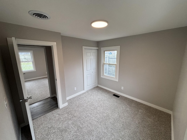 unfurnished bedroom featuring multiple windows, carpet floors, and a closet