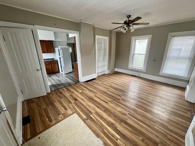 unfurnished living room with crown molding, dark hardwood / wood-style floors, and ceiling fan