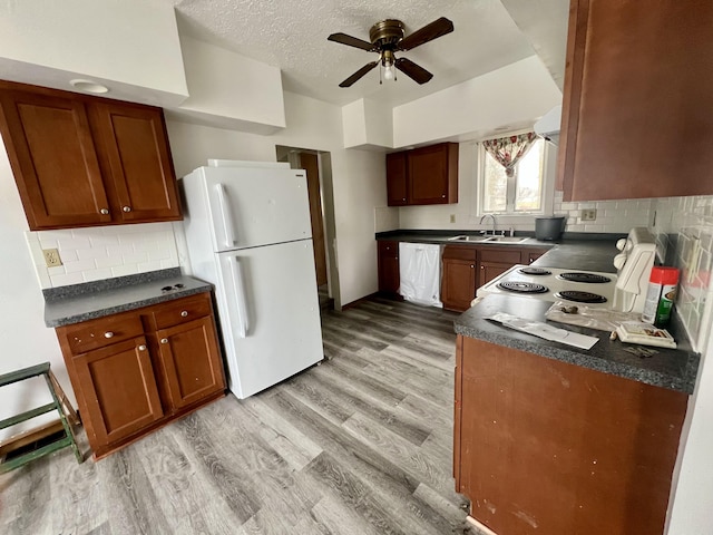 kitchen featuring sink, white appliances, light hardwood / wood-style flooring, ceiling fan, and a textured ceiling