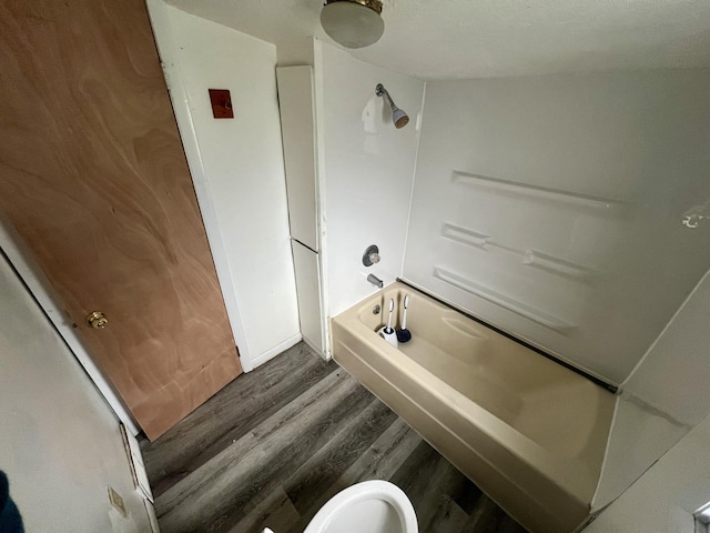 bathroom with shower / tub combination, wood-type flooring, and toilet