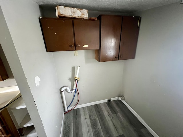 laundry room with cabinets, wood-type flooring, hookup for a washing machine, and a textured ceiling