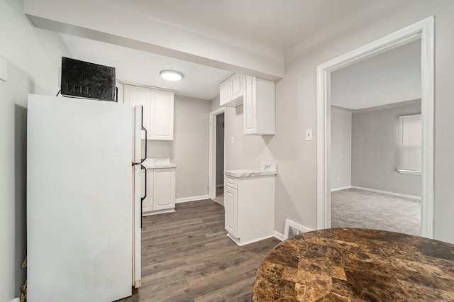 kitchen with white cabinetry, dark hardwood / wood-style floors, and white fridge