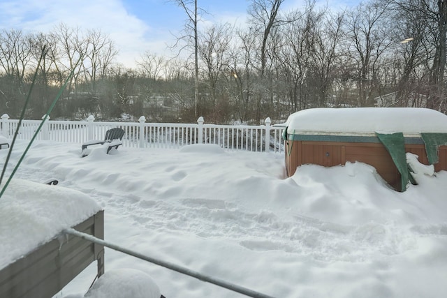 snowy yard with fence and a hot tub