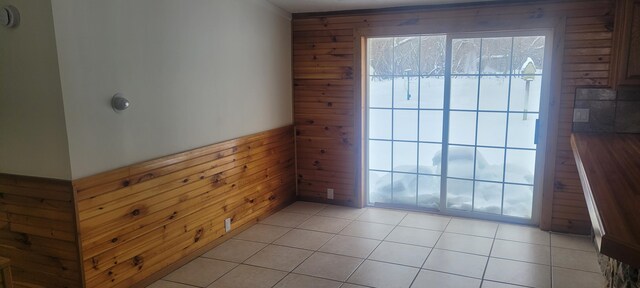 unfurnished room with light tile patterned floors and wooden walls