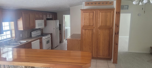 kitchen featuring sink, white appliances, kitchen peninsula, and light tile patterned flooring