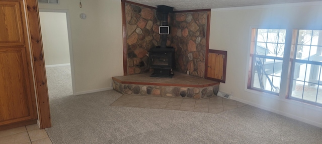 unfurnished living room featuring light colored carpet, ornamental molding, a textured ceiling, and a wood stove