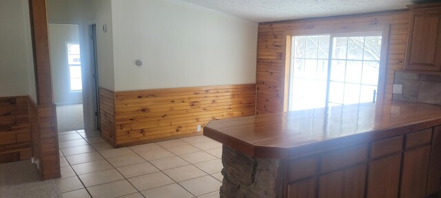 kitchen featuring light tile patterned floors, a textured ceiling, and wood walls