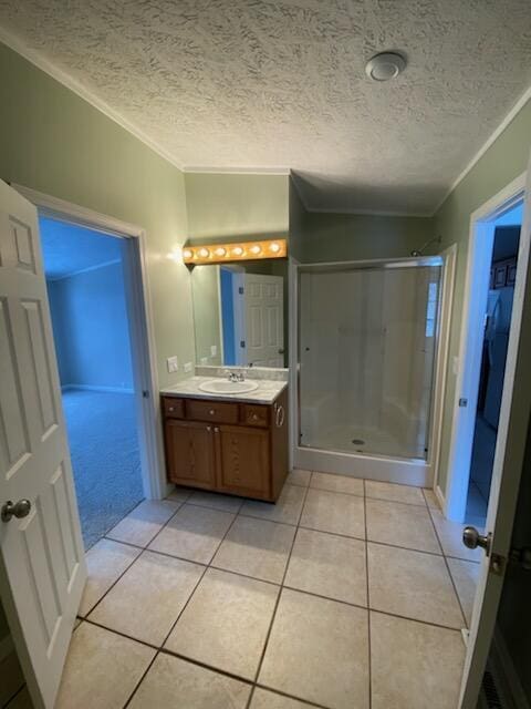 bathroom with vanity, walk in shower, crown molding, tile patterned floors, and a textured ceiling