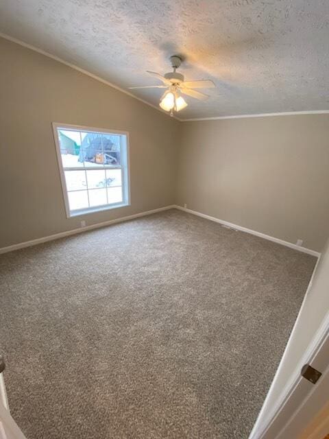 carpeted spare room featuring ceiling fan, ornamental molding, vaulted ceiling, and a textured ceiling