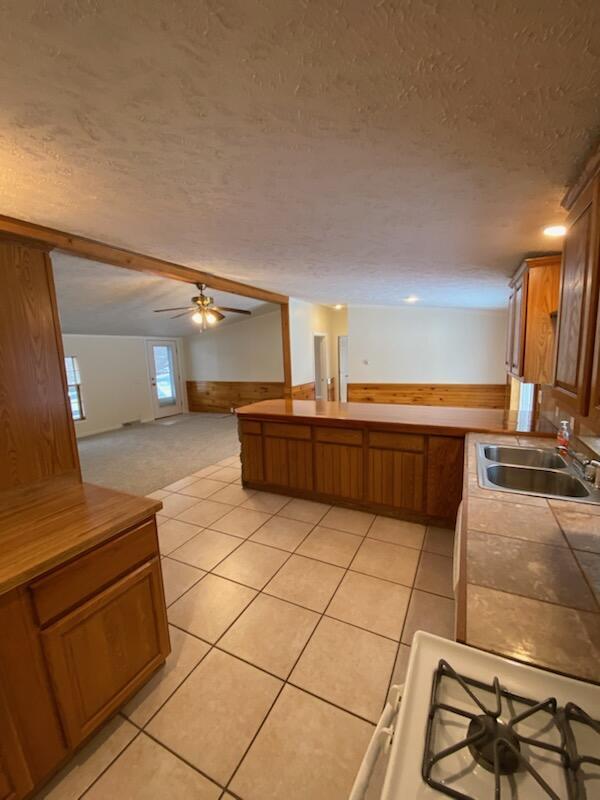 kitchen with light tile patterned flooring, sink, ceiling fan, and a textured ceiling