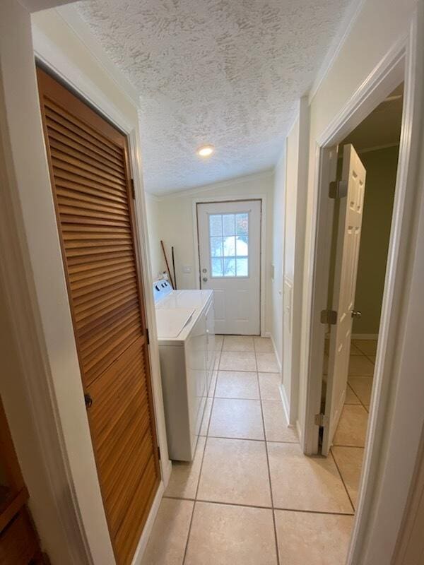 laundry area featuring independent washer and dryer, light tile patterned floors, and a textured ceiling