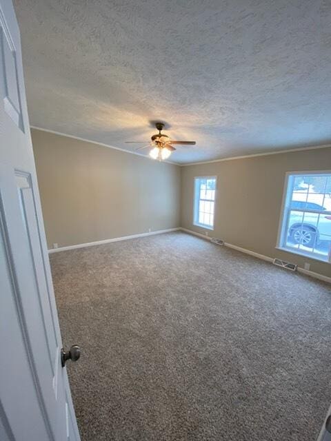 carpeted spare room with ceiling fan, ornamental molding, and a textured ceiling