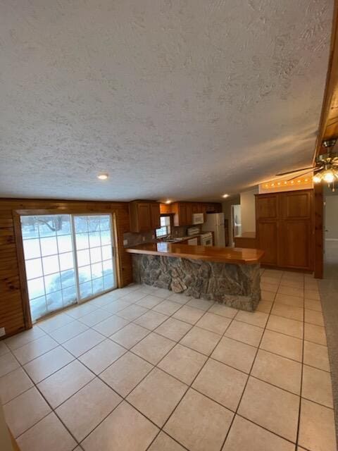 unfurnished living room with light tile patterned flooring, vaulted ceiling, and a textured ceiling