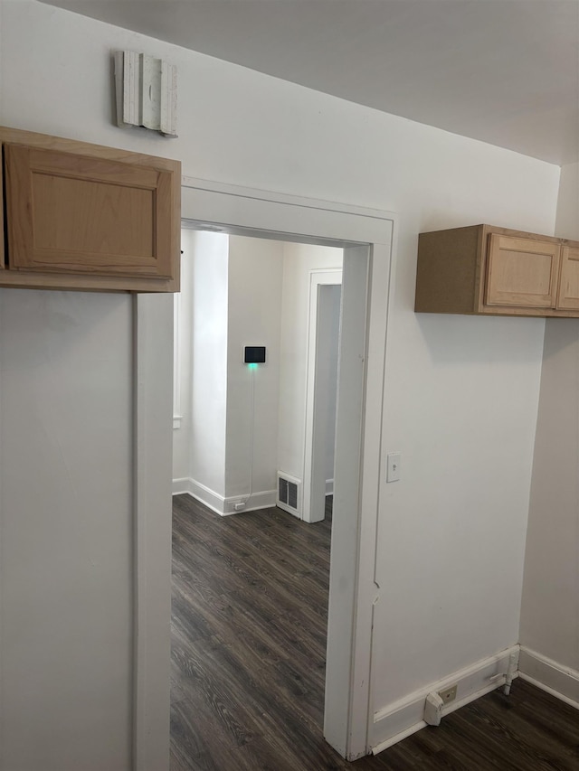 interior space with baseboards, dark wood finished floors, visible vents, and light brown cabinets