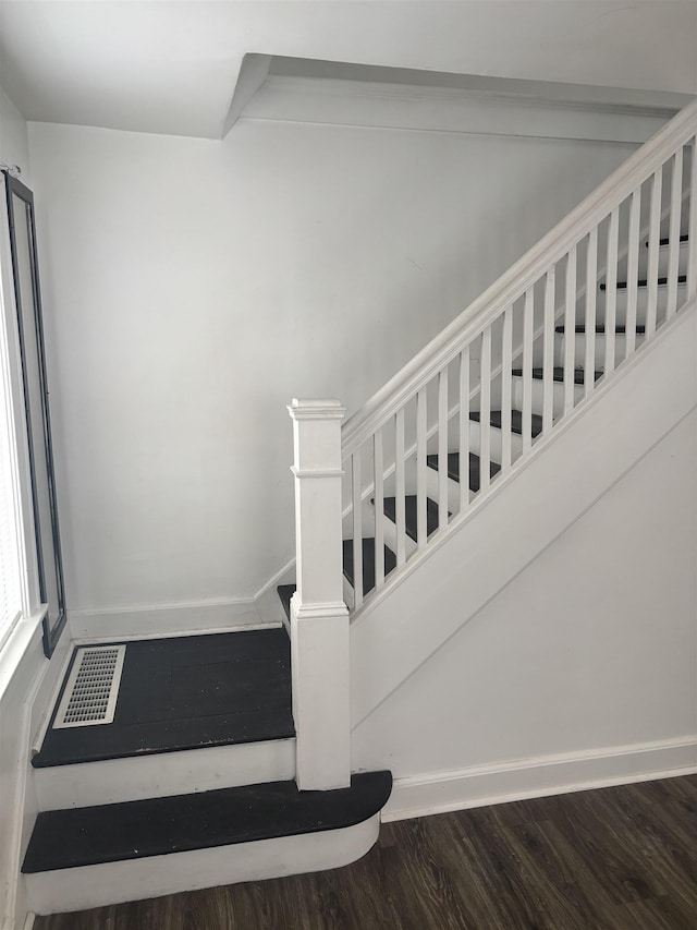stairway with baseboards, visible vents, and wood finished floors
