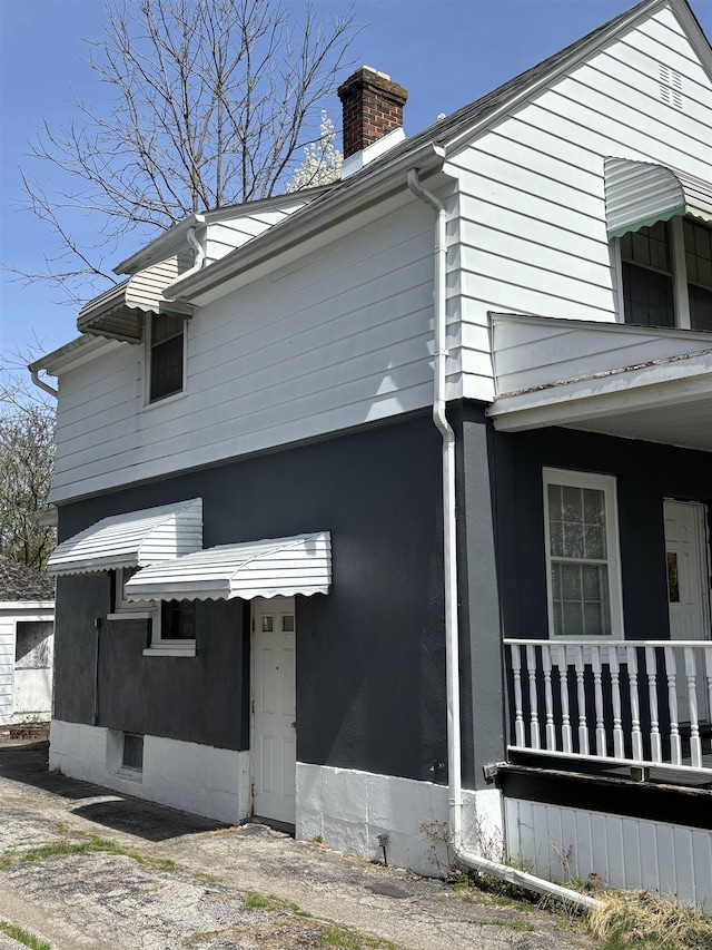view of side of home featuring a porch and a chimney